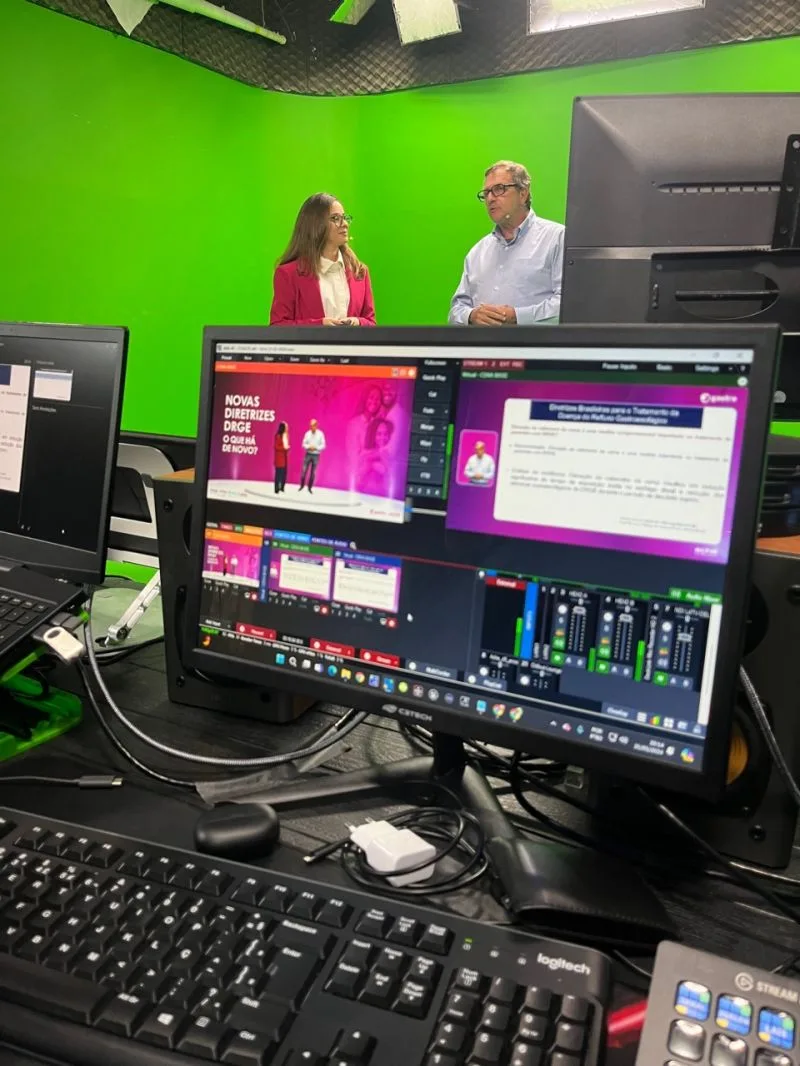 Dois apresentadores em estúdio com chroma key durante transmissão ao vivo